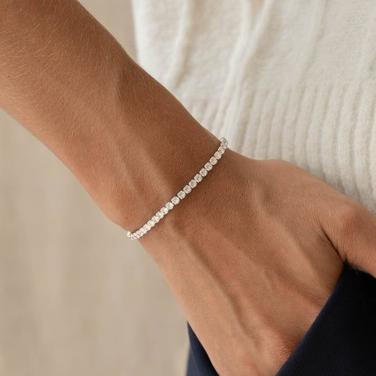 Närbild på ett gnistrande tennisarmband i silver på en handled.