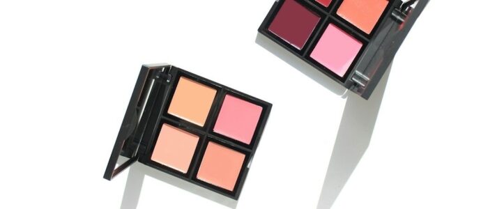 Två öppna paletter med färgkorrigerande makeup i rosa och persikotoner